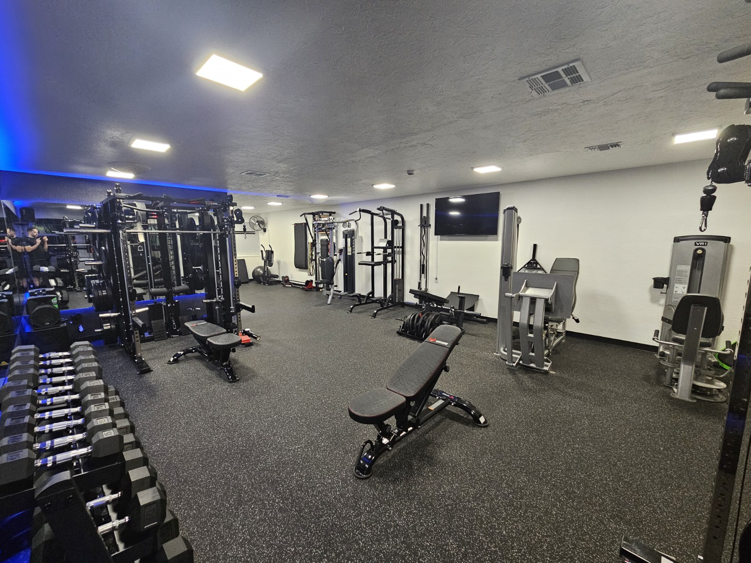 Wide interior view of the On Point Fitness private training studio, featuring weight racks and equipment.